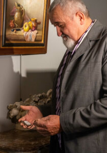 Homme qui consulte sa montre à gousset devant une peinture de nature morte